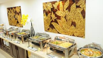 Disposição de buffet com diversas estações de comida e arte decorativa na parede.