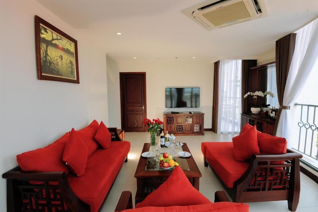 A living room with red sofas, a wooden coffee table with fruit, and a TV on a cabinet.