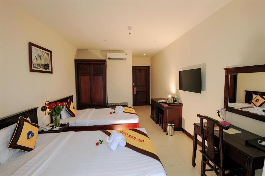 A hotel room with two beds, a desk, a chair, a TV, and a picture on the wall.