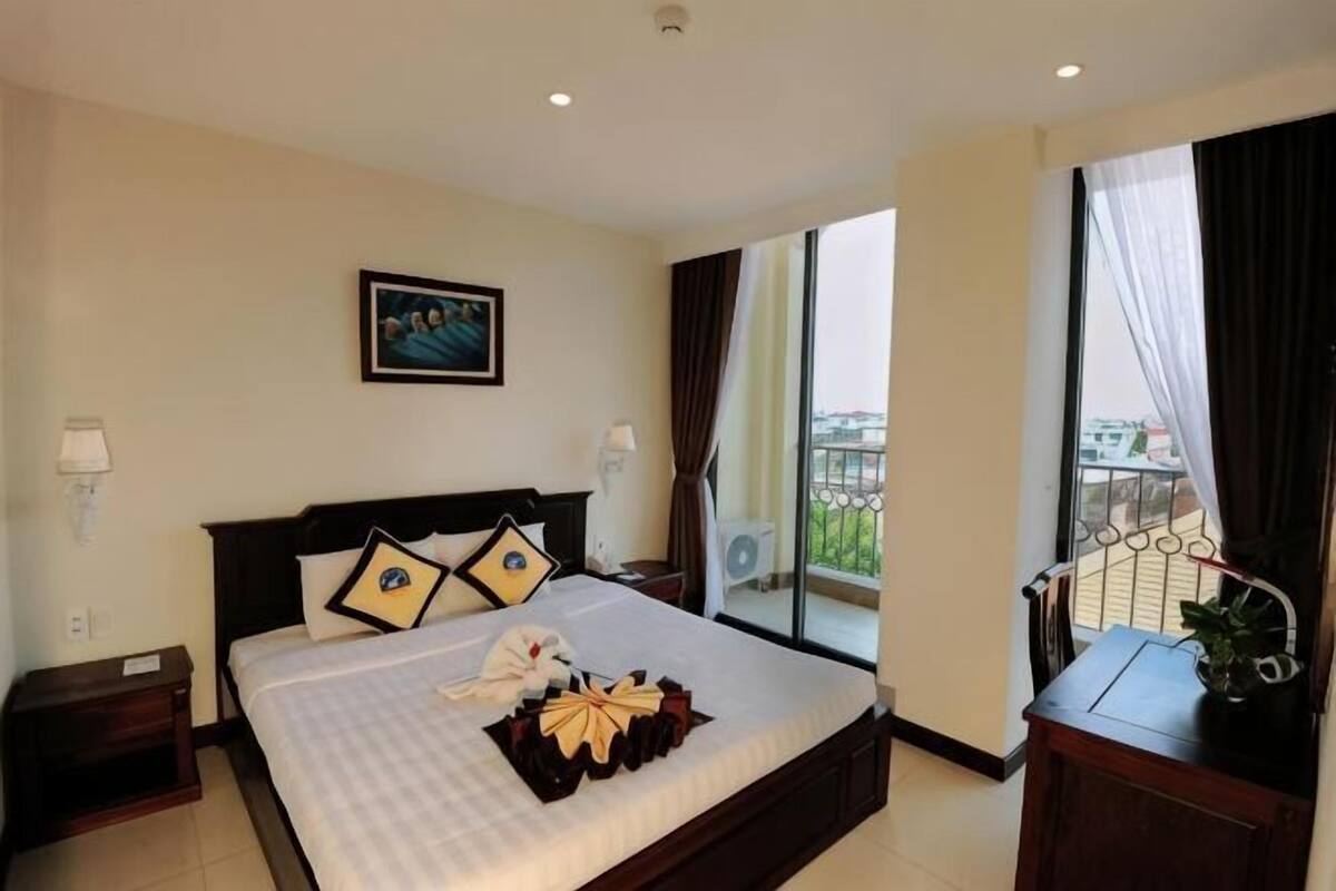 A hotel room with a large bed, a view of the city, and a balcony.