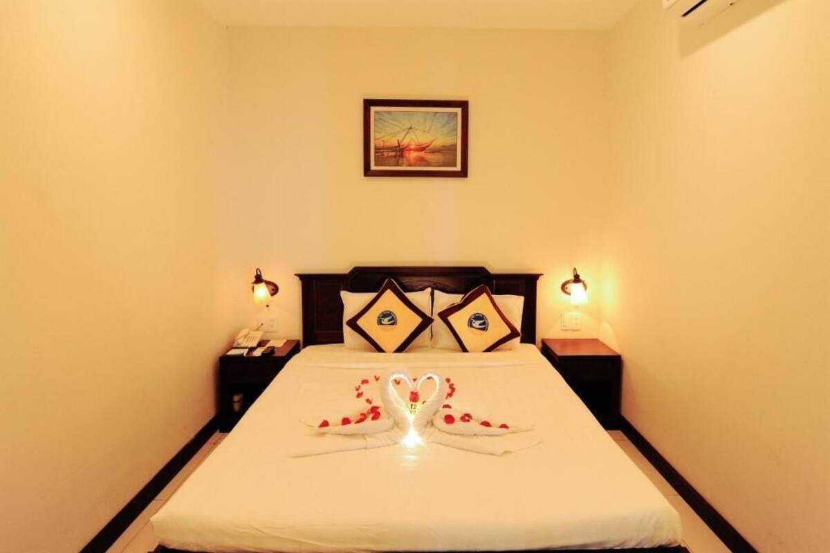 A hotel room with a neatly made bed, two bedside tables with lamps, a framed picture on the wall, and a simple, clean design.