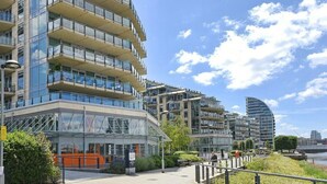 Un edificio moderno de varios pisos con balcones y ventanas amplias, cerca de la costa.