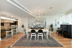 A modern dining area with a round table, white chairs, and a large floral painting on the wall. - Luxury City Apartment in London Battersea Reach (London)