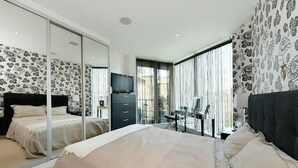 Un dormitorio moderno con una cama grande, un televisor, un aparador y un balcón con vistas.