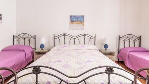 A double room with two beds, each with a purple bedspread, a central bed with a patterned quilt, and a painting on the wall. - 4085 Villa Teresa Portoselvaggio by Barbarhouse (Nardò)