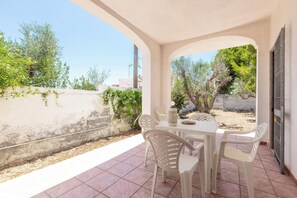 A covered outdoor seating area with a table and chairs, a potted plant, and a view of the surrounding landscape. - 4085 Villa Teresa Portoselvaggio by Barbarhouse (Nardò)
