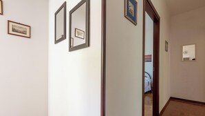 A hallway with framed pictures on the walls, a door leading to another room, and a tiled floor. - 4085 Villa Teresa Portoselvaggio by Barbarhouse (Nardò)
