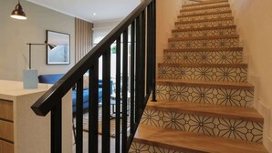 A staircase with geometric patterned tiles, a black handrail, and a modern light fixture.