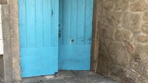A blue door with the number 1733 above it, set in a stone wall with a cobblestone floor.