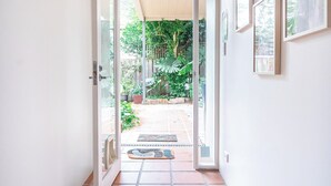 A hallway with a tiled floor leading to an open door to a garden area. - The Newtowner - Stylish Home in the heart of Newtown! (Newtown)