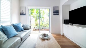 A modern living room with a sofa, a coffee table, and a TV. - The Newtowner - Stylish Home in the heart of Newtown! (Newtown)