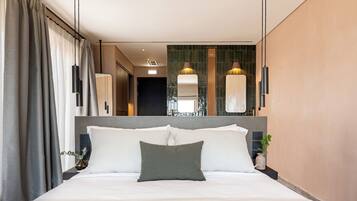 A modern hotel room with a large bed, a headboard, and a nightstand with a vase.