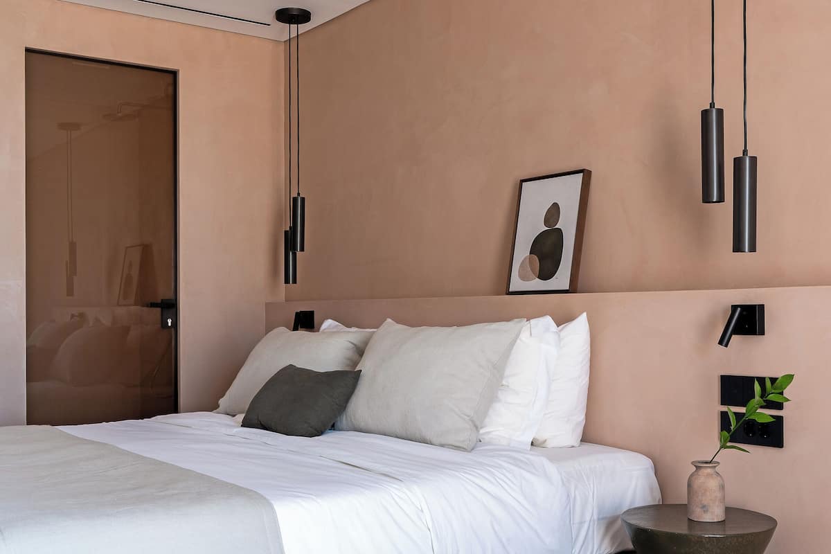 A modern bedroom with a bed, bedside table, and pendant lights.