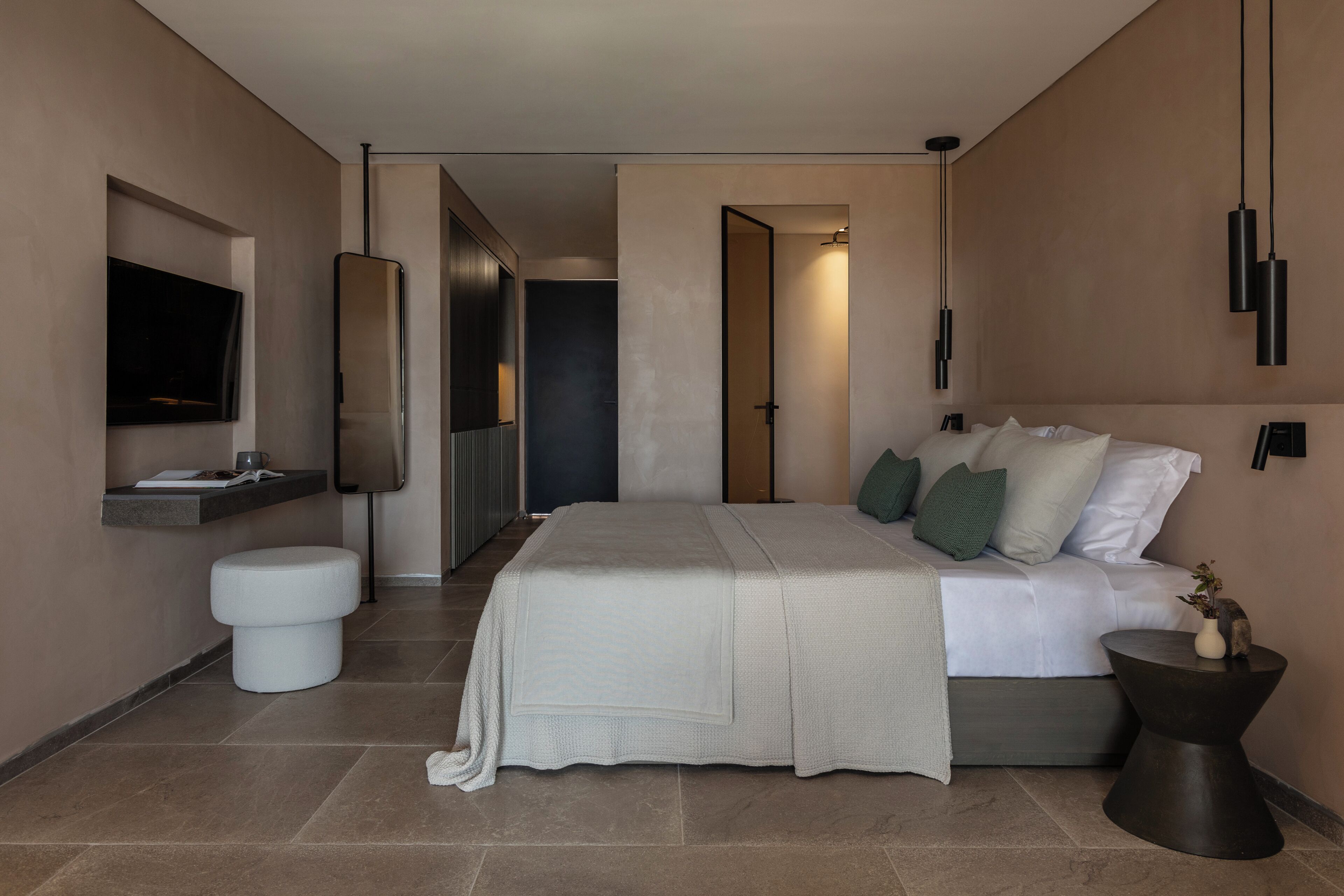 A modern bedroom with a bed, bedside table, and a TV mounted on the wall.