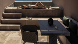 A rooftop terrace with a view of the sea, a table with a chair, and a person relaxing. - Tetra Retreat (Kefalonia)