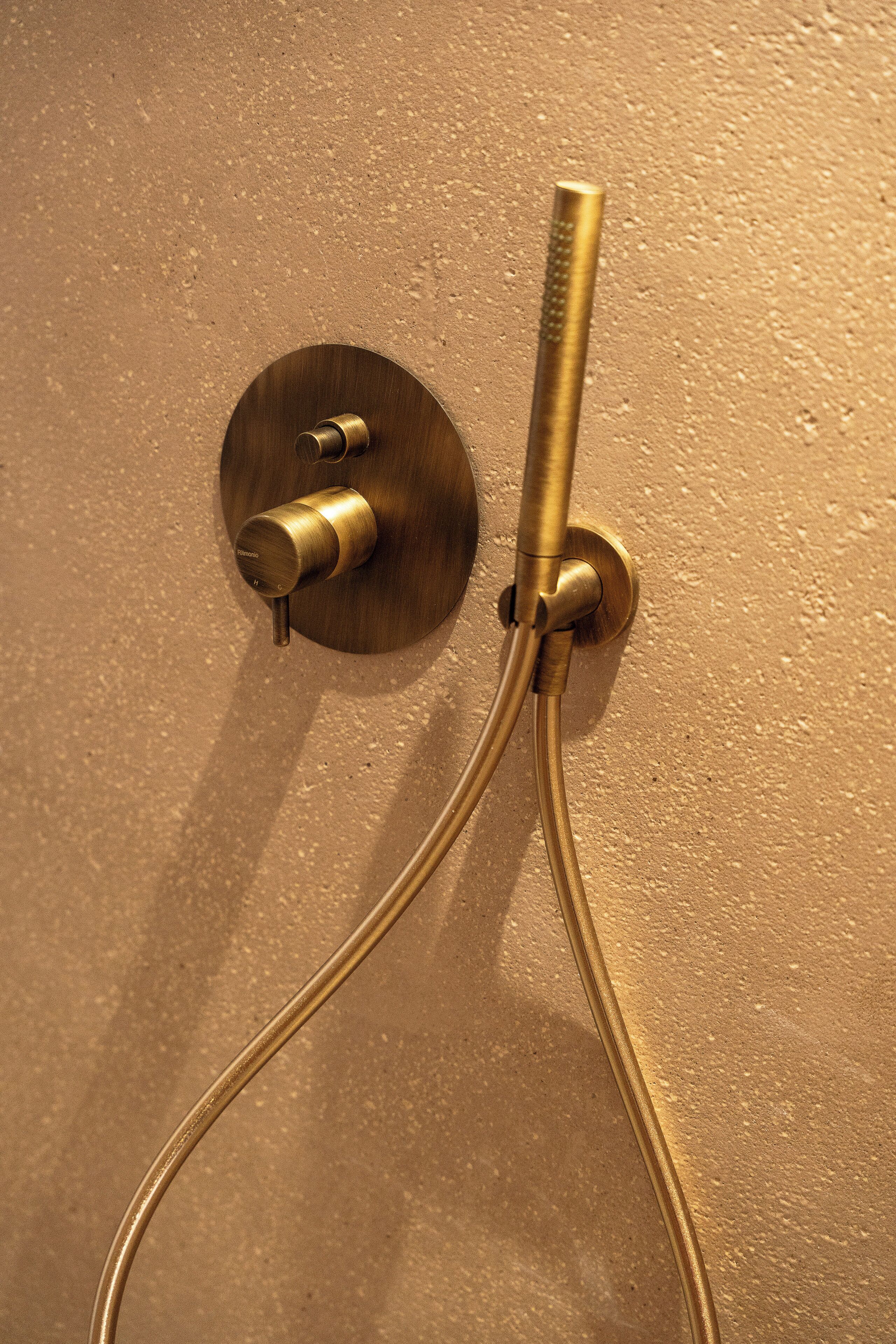 Un control de ducha de bronce con dos mandos y un manguera flexible.