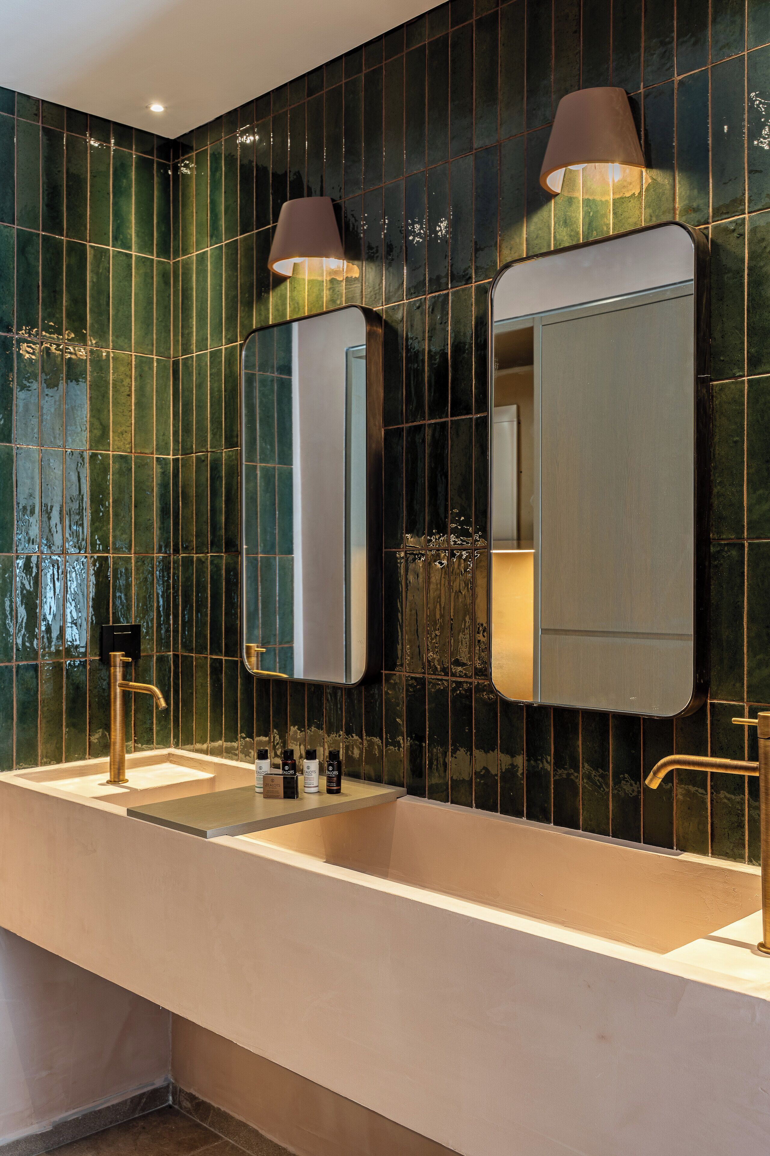 A bathroom with two sinks, a mirror, and a wall-mounted lamp.