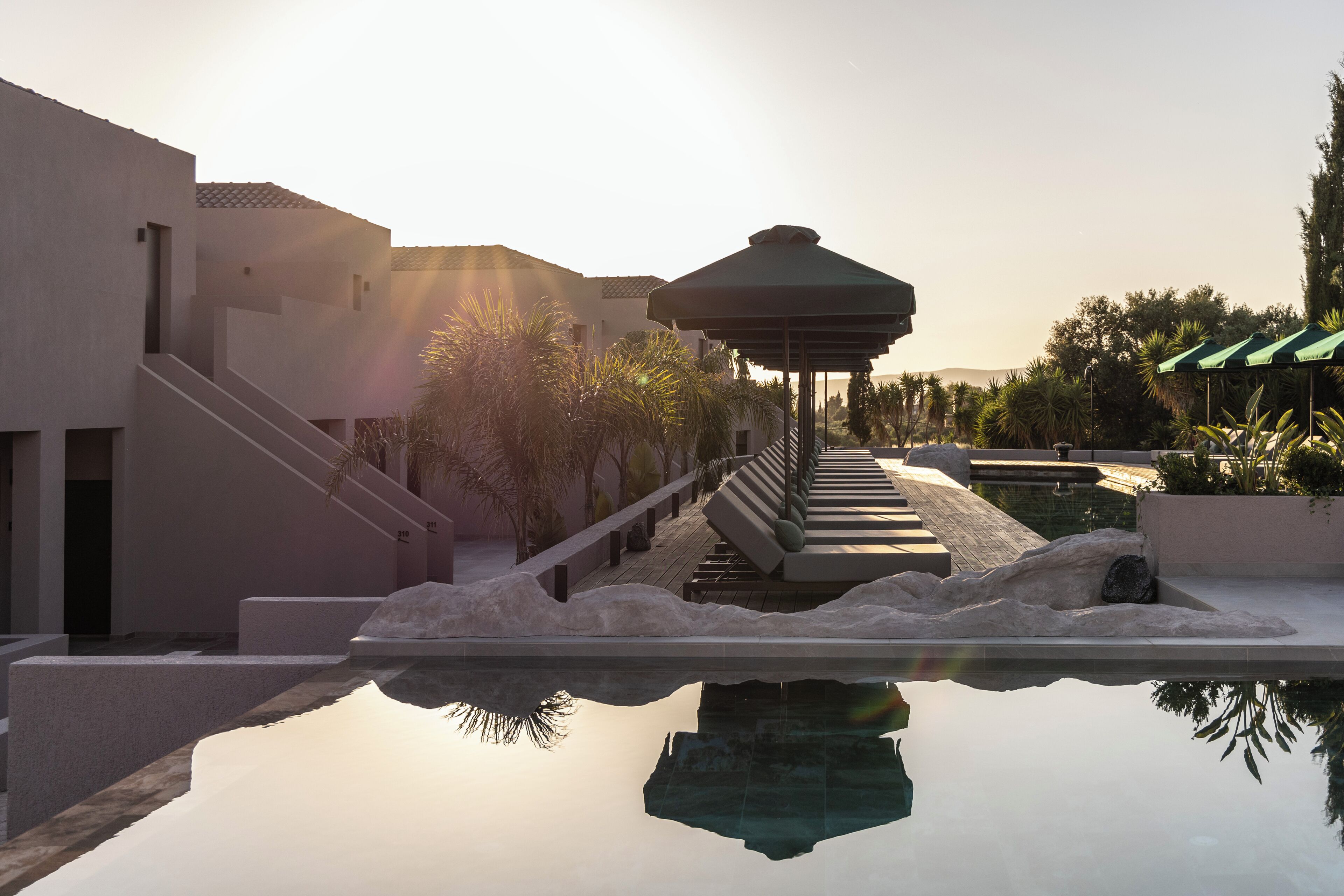 A pool with a gazebo, steps leading to a building, and surrounding greenery.