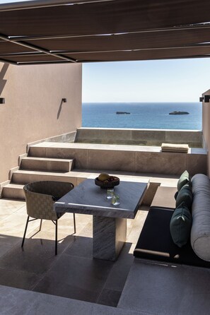 Una terraza con mesa, sillas y sofá, con vista al mar.