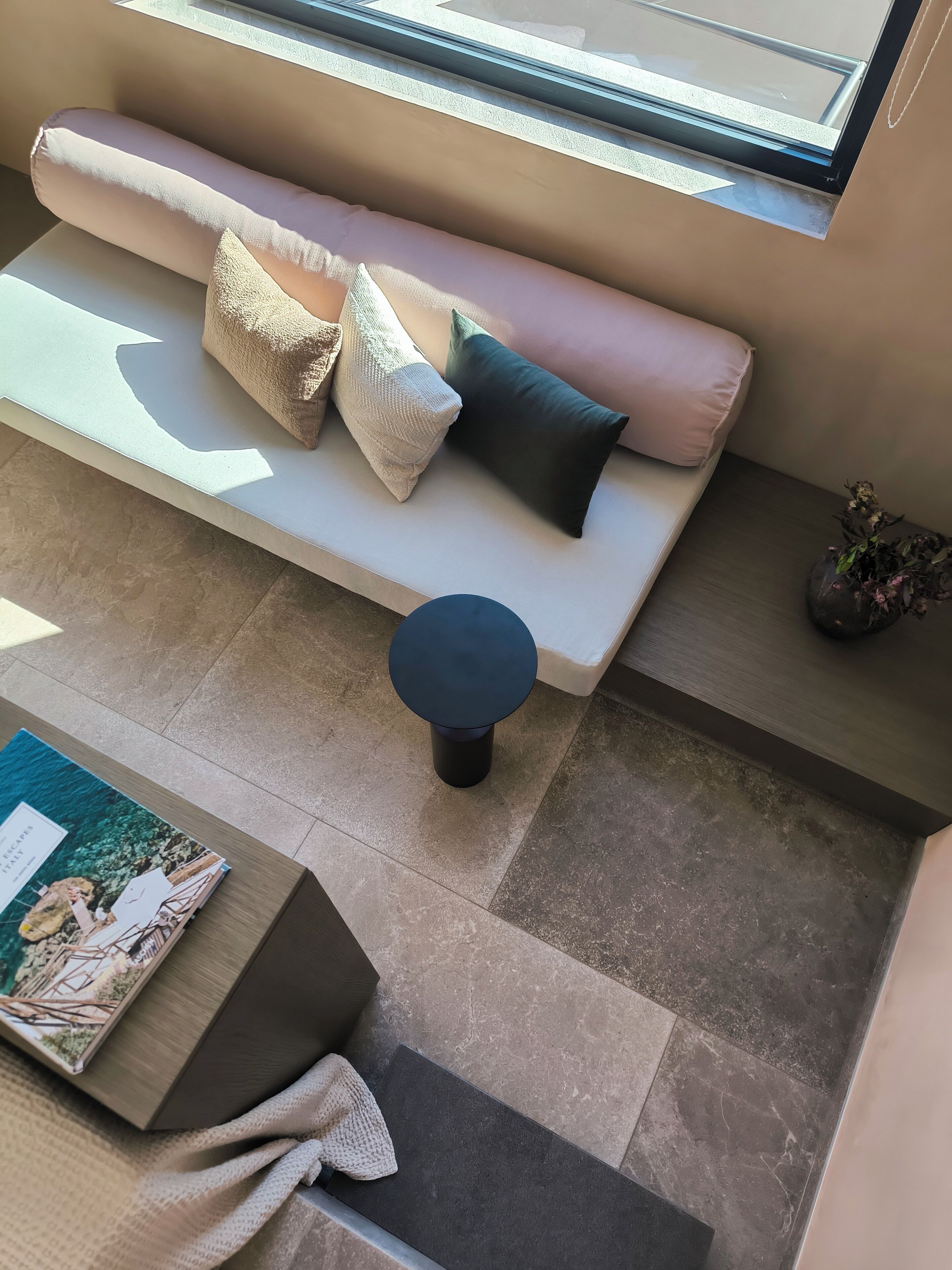 A modern living area with a sofa, cushions, a round table, and a magazine.