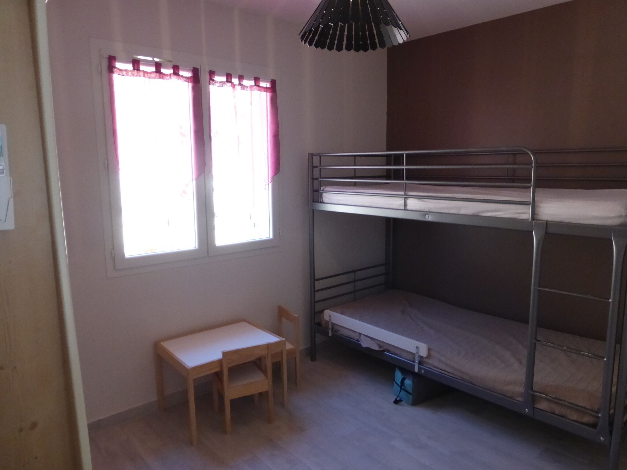 A bunk bed room with a window, a desk, and a chair.