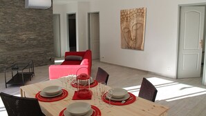 Un soggiorno moderno con angolo da pranzo, un divano rosso e un'ampia opera d'arte in legno sulla parete.