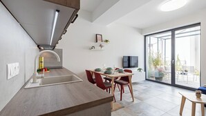 A modern kitchen with a built-in stove, a dining area with red chairs, and a large sliding glass door leading to a balcony. - Fully equipped apartments with Terraces, Free garage parking, Netflix & AC - by Apartmány Šlapanice cz (Slapanice)