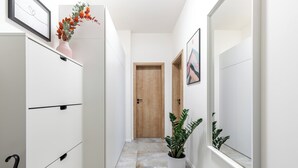 A narrow hallway with a white cabinet, a wooden door, and a potted plant. - Fully equipped apartments with Terraces, Free garage parking, Netflix & AC - by Apartmány Šlapanice cz (Slapanice)