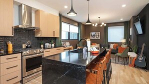 A modern kitchen with a central island, stainless steel appliances, and pendant lighting.