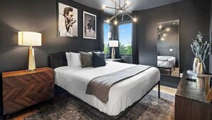 A modern bedroom with a large bed, dark walls, and a chandelier.