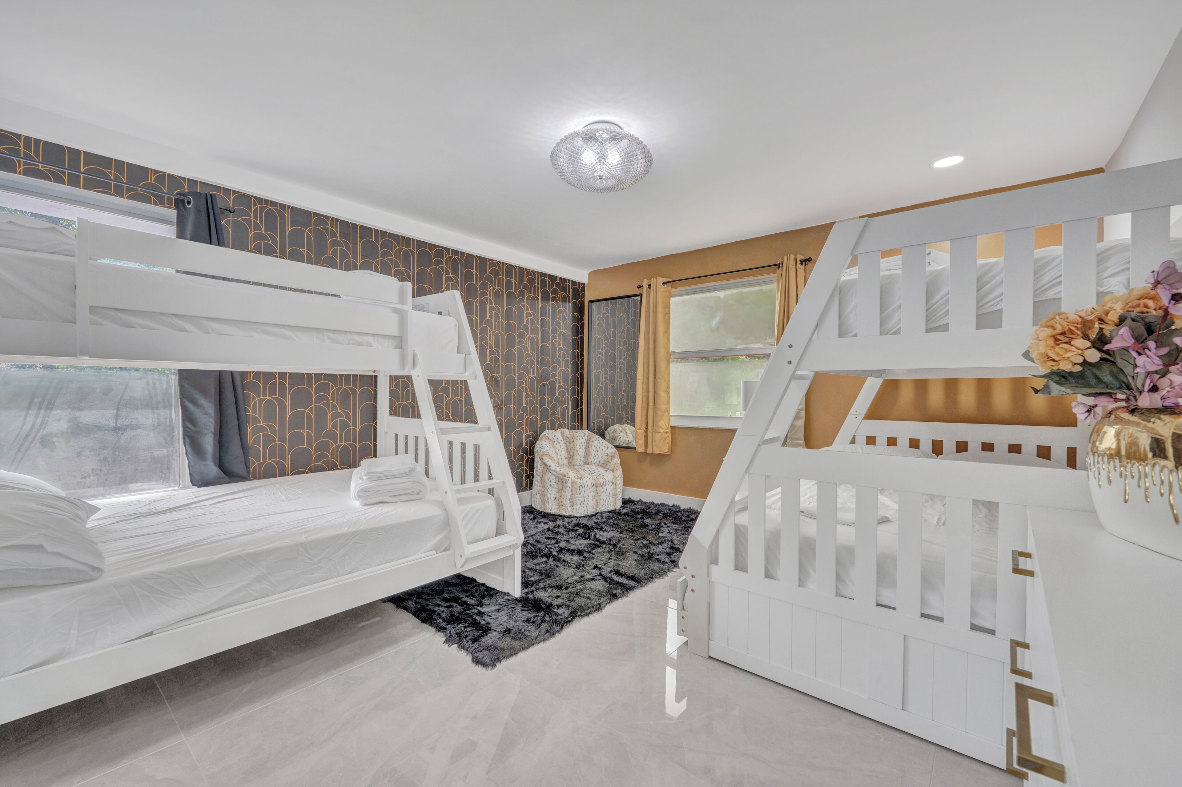 A child’s room with bunk beds, a small chair, and a decorative wall.