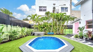 Un giardino sul retro con piscina, prato verde e recinzione in legno.