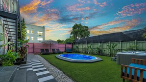 Un giardino con piscina, un pontile in legno e una vasca idromassaggio.