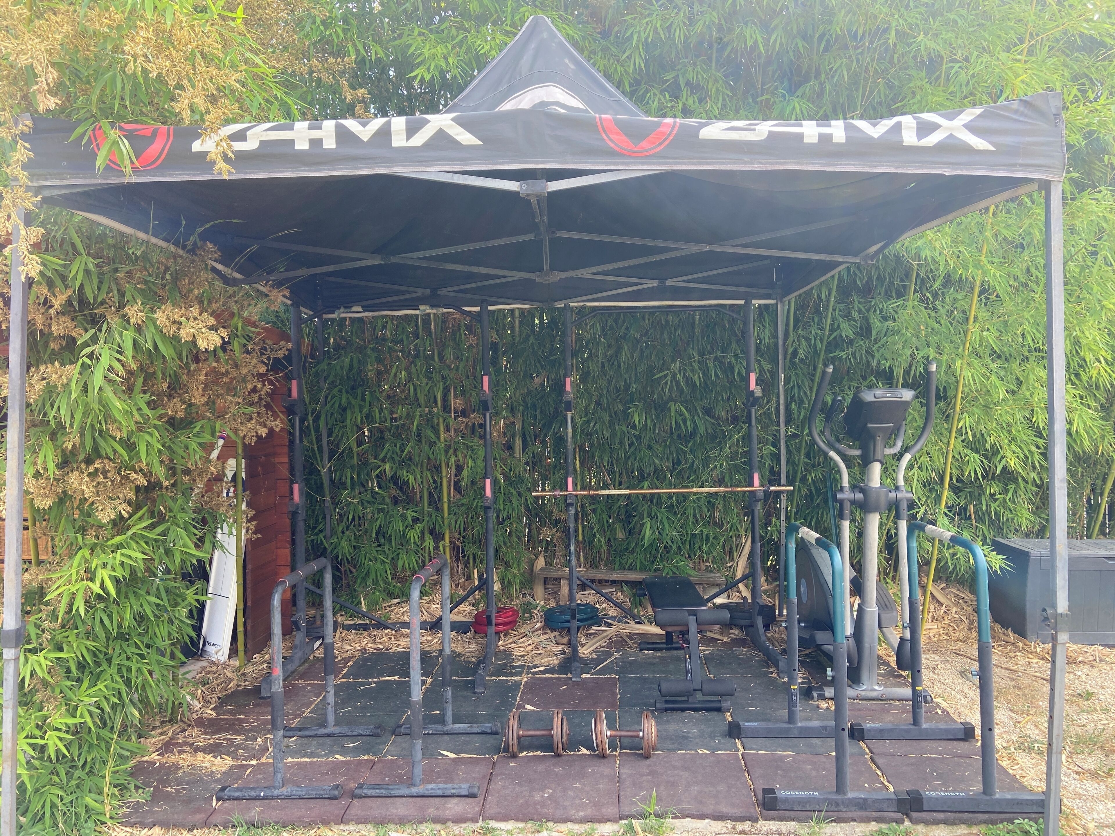 Un espace de remise en forme en plein air, doté d’une zone abritée, d’équipements d’exercice et d’un décor en bambou.