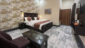 Un dormitorio moderno con cama, mesitas de noche, una mesa de centro de vidrio, un rincón de descanso y un armario.