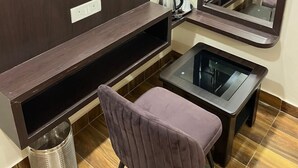 Una habitación compacta con tocador de madera oscura, un espejo, una mesita pequeña y una silla morada.