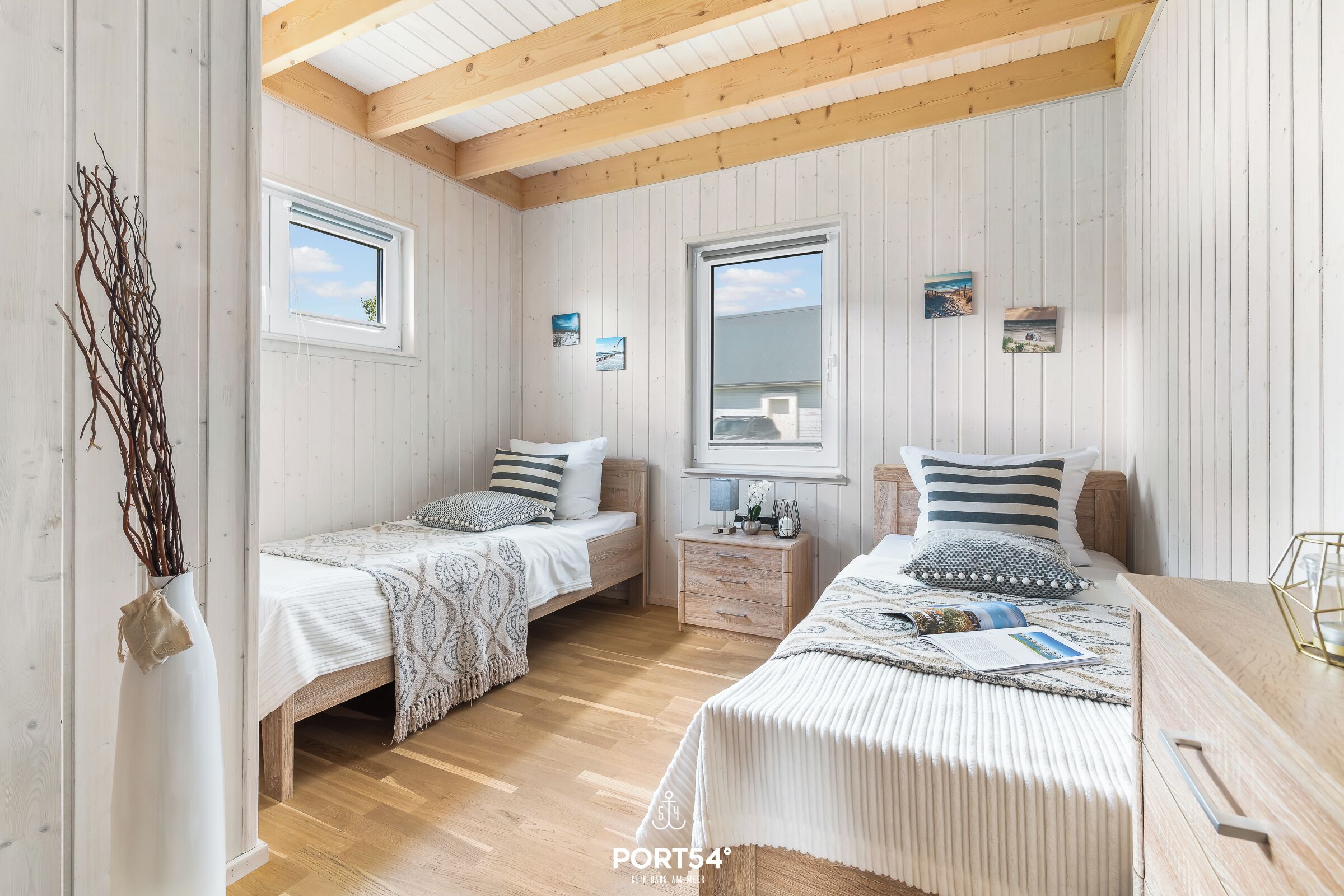 Ein gemütliches Schlafzimmer mit zwei Einzelbetten, Holzboden und einem großen Fenster.