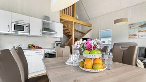 Eine moderne Küche mit weißen Schränken, einer Holztreppe und einem Essbereich mit einem Holztisch für zwei Personen.