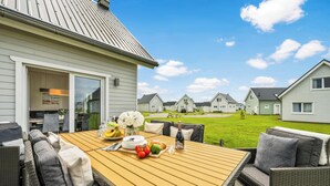 Eine Terrasse mit einem Holztisch, der zum Essen gedeckt ist, umgeben von Korbmöbeln.