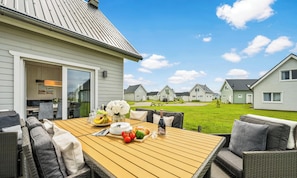 A patio with a table set for dining, surrounded by wicker furniture. - Sanfte Brise- Infrared Sauna, Fireplace, Shower Room, Bathtub, Terrace, Parking (Olpenitz)