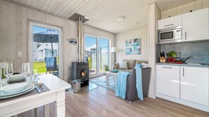 Moderni keittiö, jossa on valkoiset kaapit, sisäänrakennettu mikroaaltouuni ja liesi.