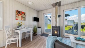 Tunnelmallinen huone, jossa on puusisustus, takka, ruokailutila ja suuri ikkuna, josta avautuu näkymä ulos.