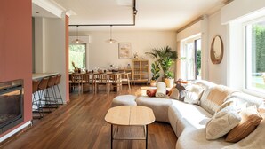 Amplia sala de estar con chimenea, una mesa de comedor y un ventanal con vistas al exterior.