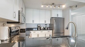 A modern kitchen with white cabinets, stainless steel appliances, and a granite countertop. - Oceanfront 3bed 3bath condo! 19th floor. Amazing views indoor & outdoor pools (Myrtle Beach)