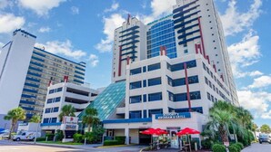 A hotel with a modern design, featuring a glass facade and multiple floors. - Oceanfront 3bed 3bath condo! 19th floor. Amazing views indoor & outdoor pools (Myrtle Beach)