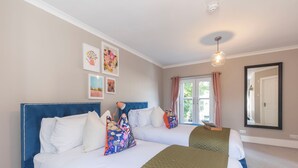 A bedroom with two beds, a large mirror, and artwork on the walls. - Elliot Oliver - Comfortable Five Bedroom Town Centre House With Garden & Garage (Cheltenham)