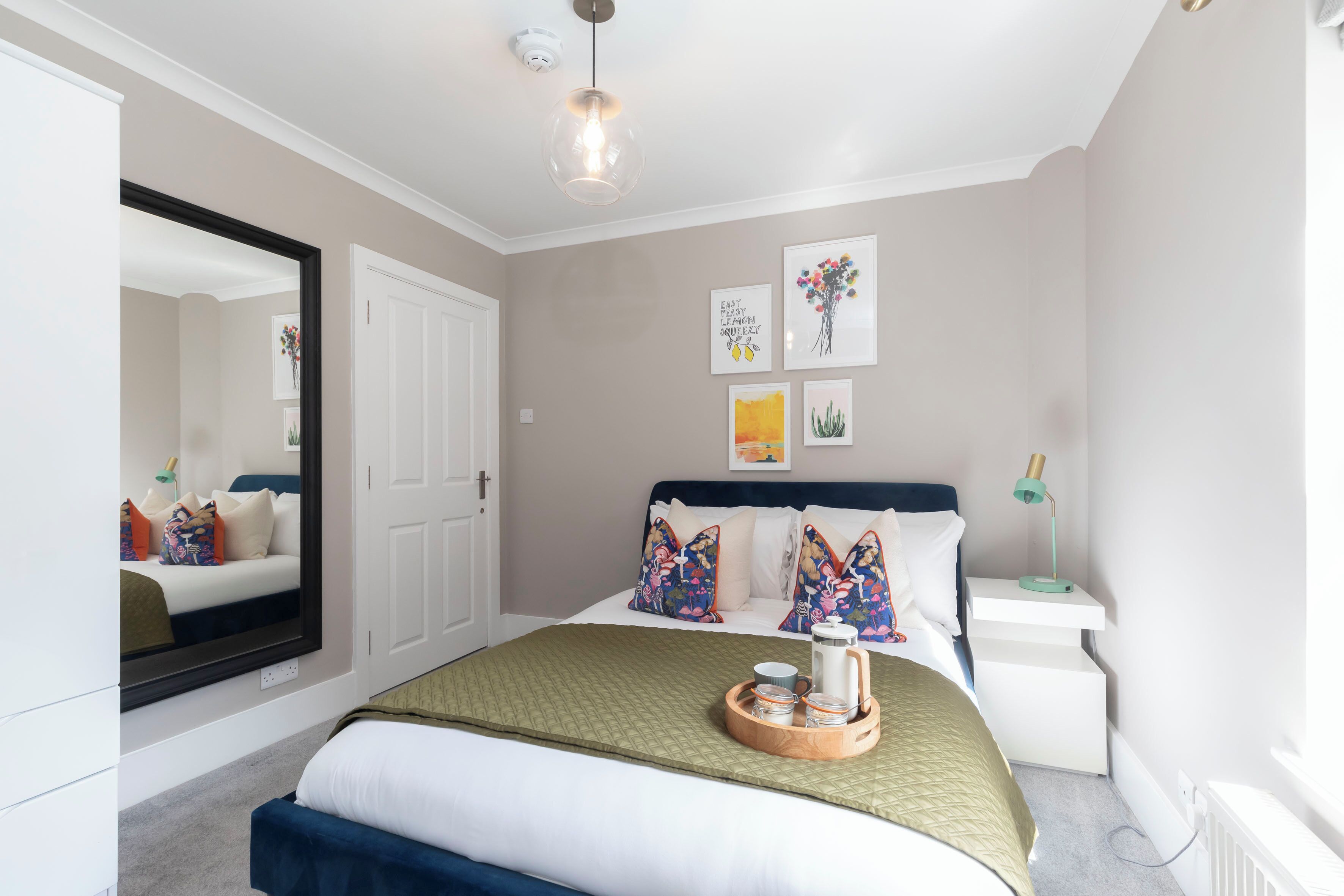 Une chambre à coucher bien rangée, avec un lit, une table de chevet et un miroir.