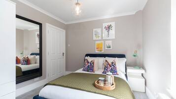 Une chambre à coucher bien rangée, avec un lit, une table de chevet et un miroir.