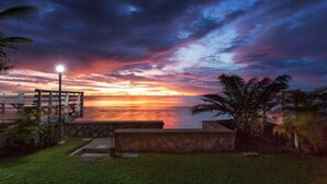 A sunset view from a balcony with a stone wall and palm trees. - Aranava Resort Huahin (Hua Hin)