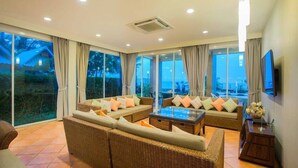 A spacious living area with wicker furniture, large windows, and a flat-screen TV. - Aranava Resort Huahin (Hua Hin)